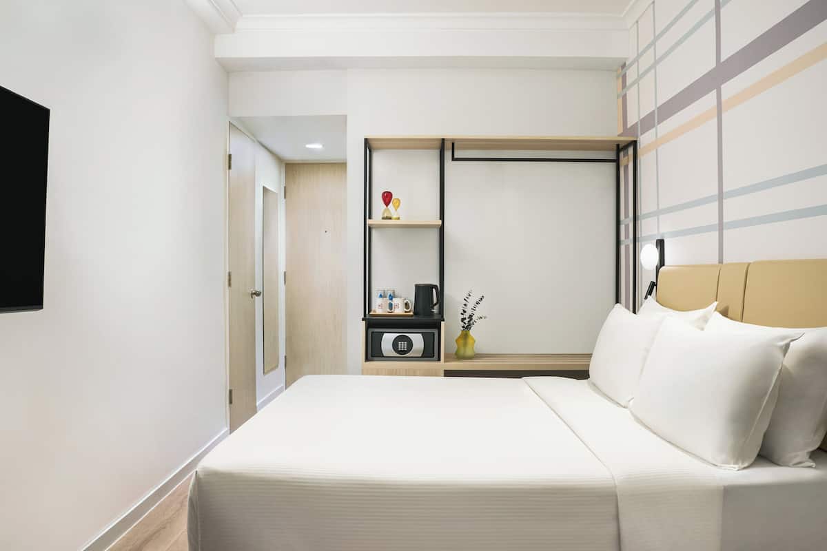 A hotel room with a bed, bedside table, and a wardrobe.
