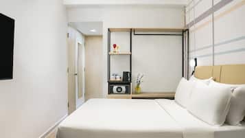 A hotel room with a bed, bedside table, and a wardrobe.