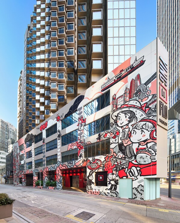 Un edificio moderno con un gran mural lateral que muestra personajes de dibujos animados y un tren.