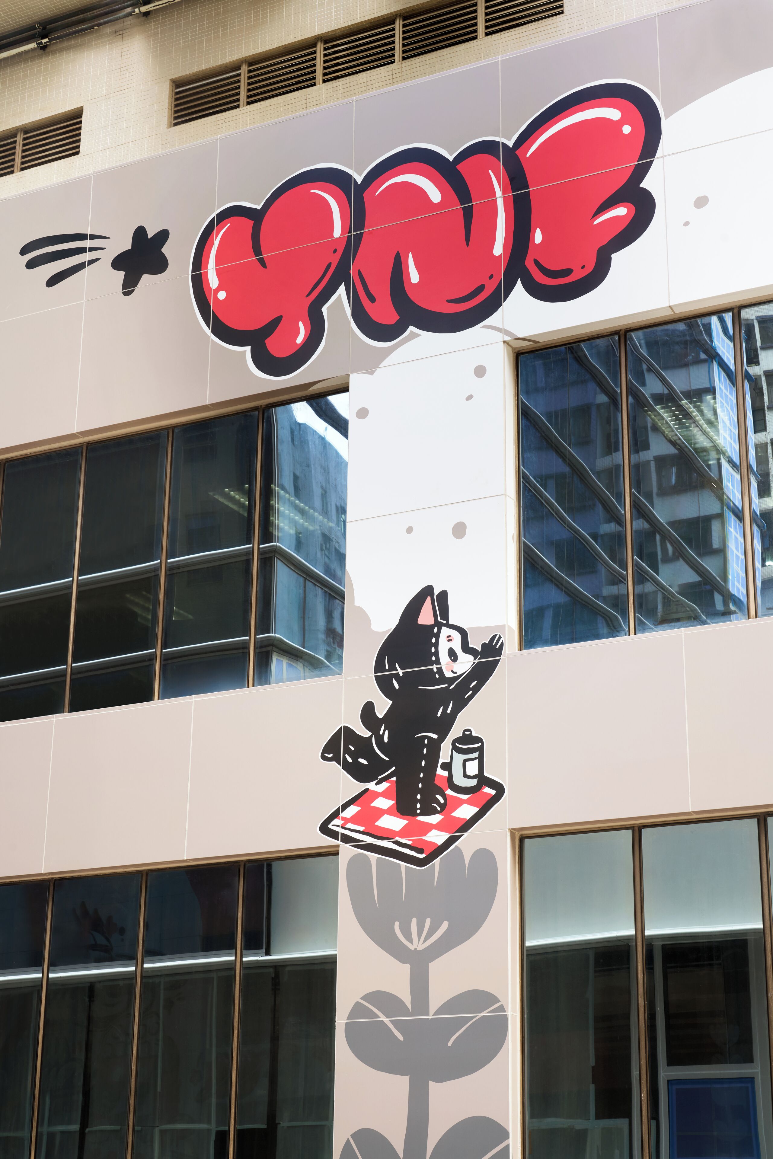 A building with a large window and a mural of a cat on a checkered table.