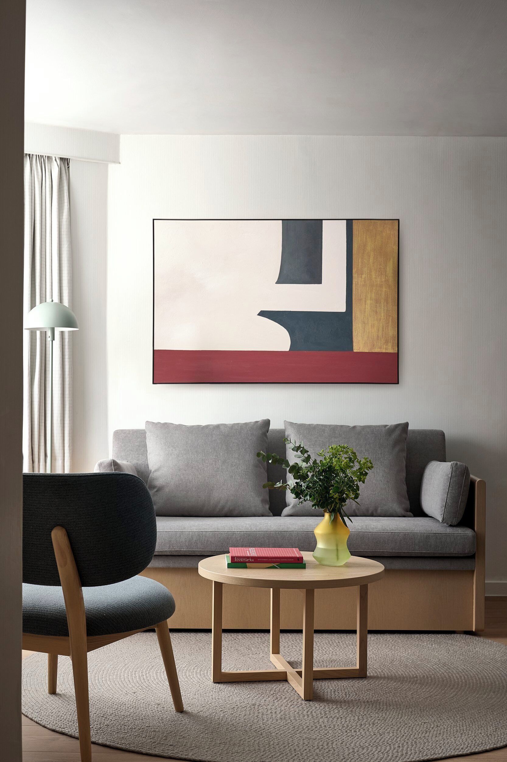 A modern living room with a grey sofa, a round wooden coffee table, and a floor lamp.