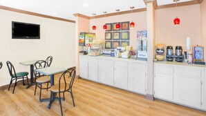 A breakfast bar with seating, a flat-screen TV, and various food items. - Americas Best Value Inn Kosciusko (Kosciusko)