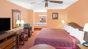 A hotel room with a bed, a desk with a television, a chair, a desk lamp, a telephone, and a ceiling fan. - Americas Best Value Inn Kosciusko (Kosciusko)