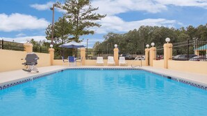 A swimming pool with lounge chairs and a barbecue grill. - Americas Best Value Inn Kosciusko (Kosciusko)