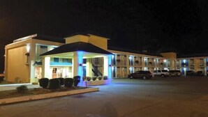 A motel with a central covered area, a staircase, and multiple parking spaces. - Americas Best Value Inn Kosciusko (Kosciusko)