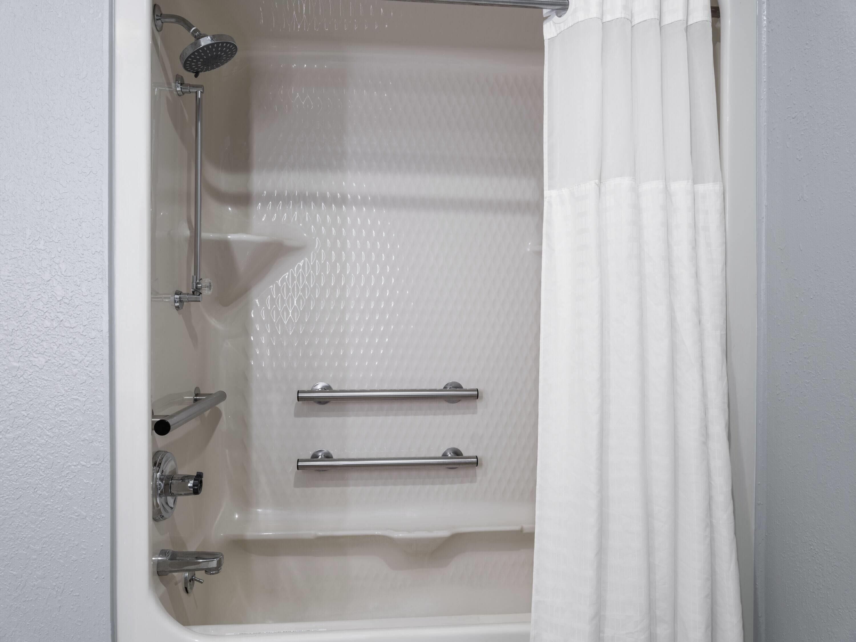 A white bathtub with a showerhead, two towel bars, and a shower curtain.