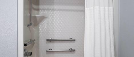 A white bathtub with a showerhead, two towel bars, and a shower curtain.