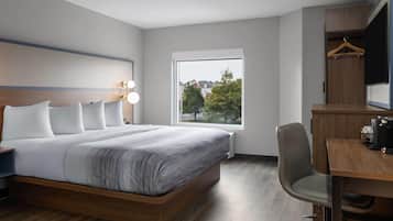 Una habitación de hotel moderna con una cama grande, un escritorio y un armario.