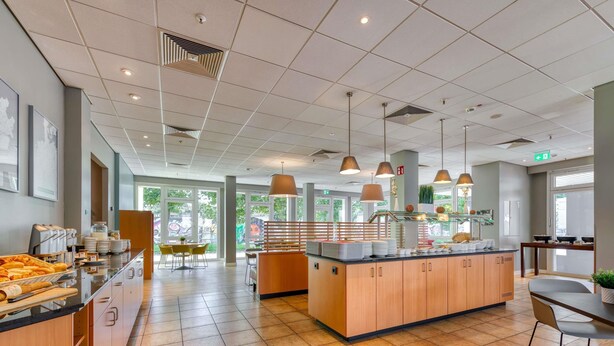 Eine moderne Hotelhalle mit einer zentralen Insellounge, Sitzbereichen und großen Fenstern.