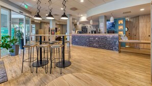 Eine moderne Hotelhalle mit Rezeption, Bar und Sitzgelegenheiten.