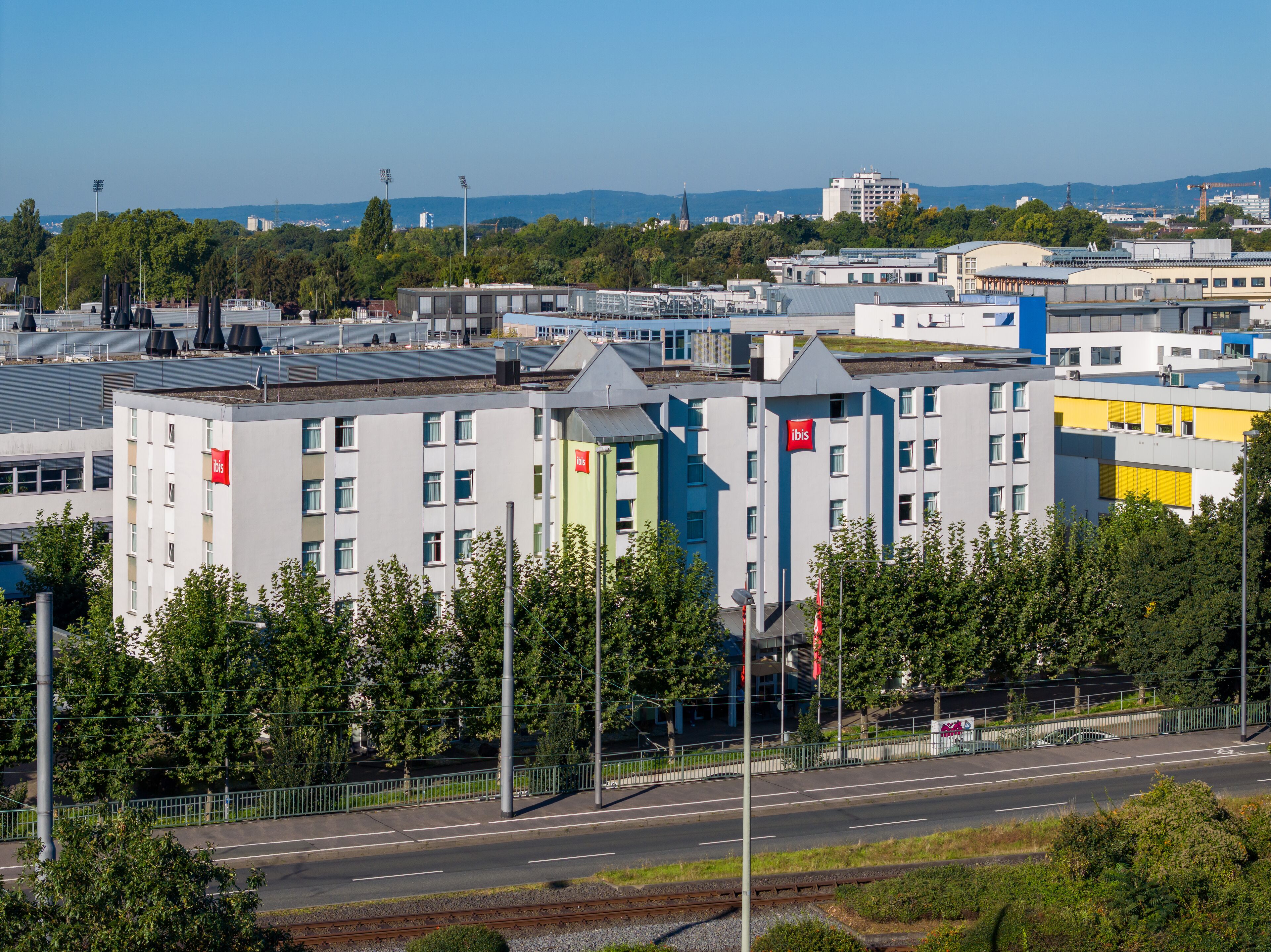 A multi-story hotel with a modern design, featuring a prominent red logo on the facade.