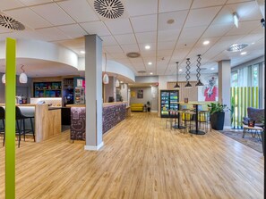 Un interior moderno con una zona de bar, asientos y una máquina expendedora.