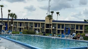 Una piscina al aire libre, sombrillas, sillones reclinables de piscina