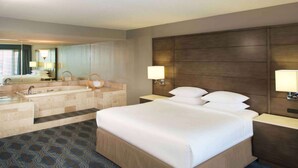 A hotel room with a large bed, a bathroom with a bathtub, a mirror, and two bedside lamps. - Doubletree by Hilton Bloomington - Minneapolis South (Bloomington)