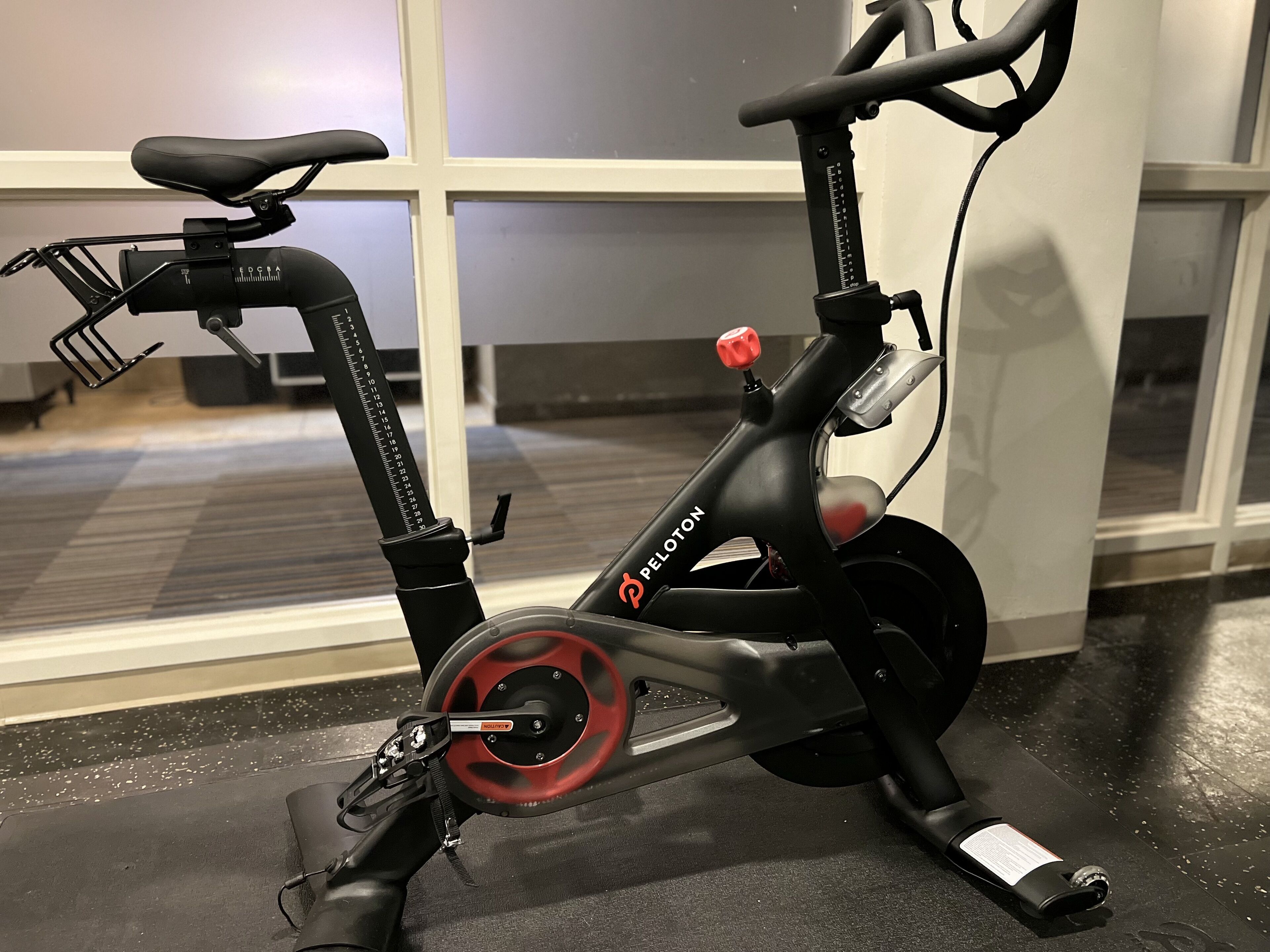 Una bicicleta estática de interior con rueda roja, estructura negra y manillar rojo.