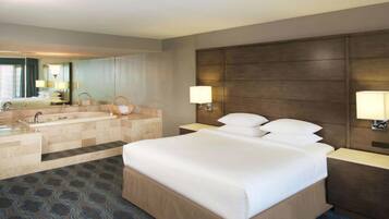 Habitación de hotel con una cama grande, una bañera, un tocador con espejo y dos lámparas de noche.