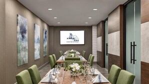 A conference room with a long table, green upholstered chairs, and a projector screen displaying 'Aspen Oak Lounge and Restaurant'. - Doubletree by Hilton Bloomington - Minneapolis South (Bloomington)