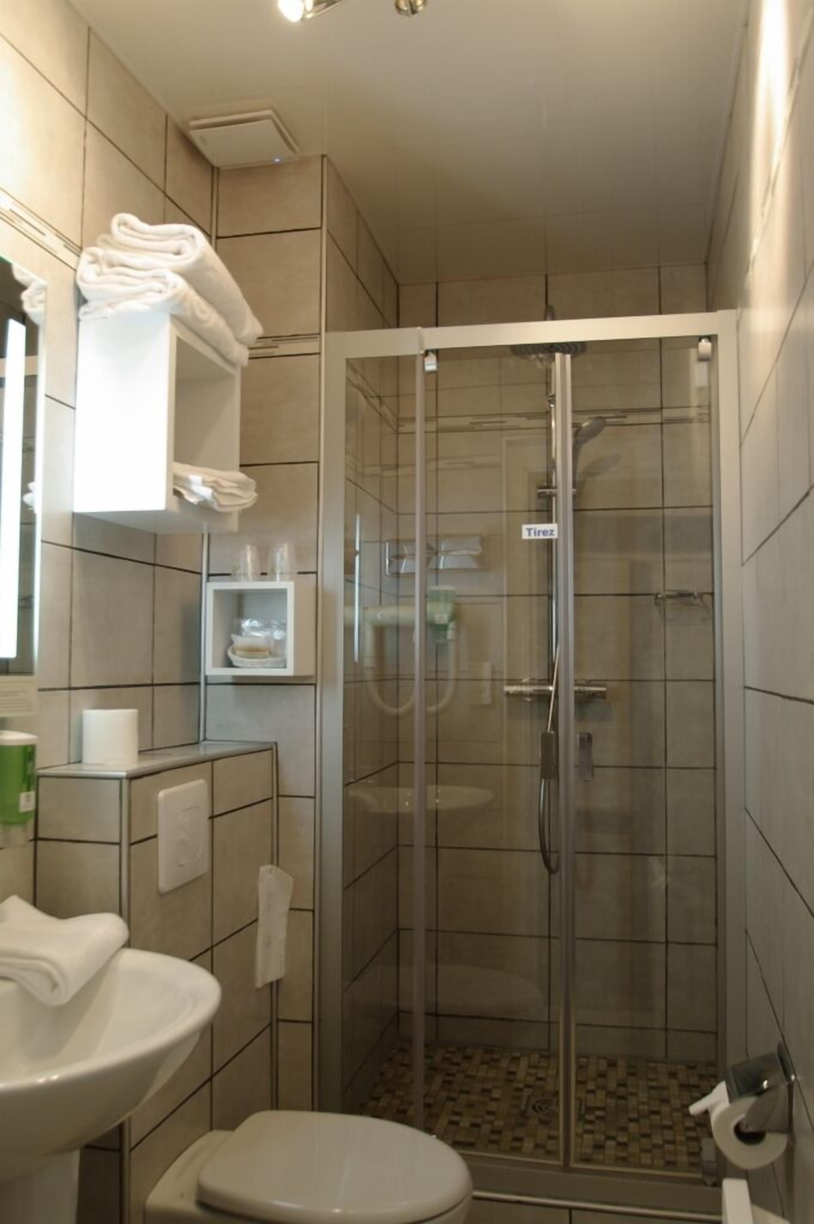 A bathroom with a glass-enclosed shower, a sink, and a toilet.