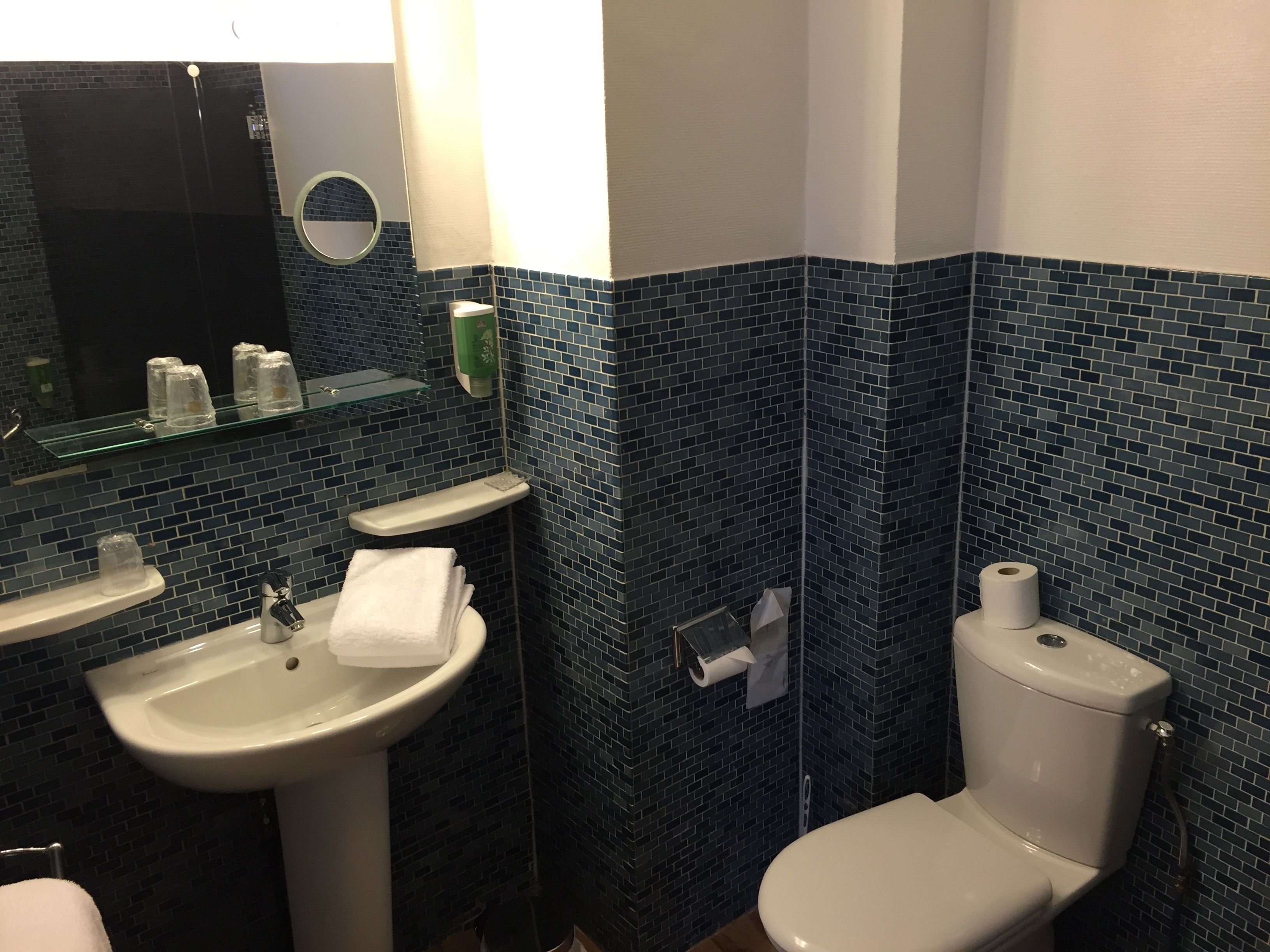 A bathroom with a white sink, toilet, and a mirror.