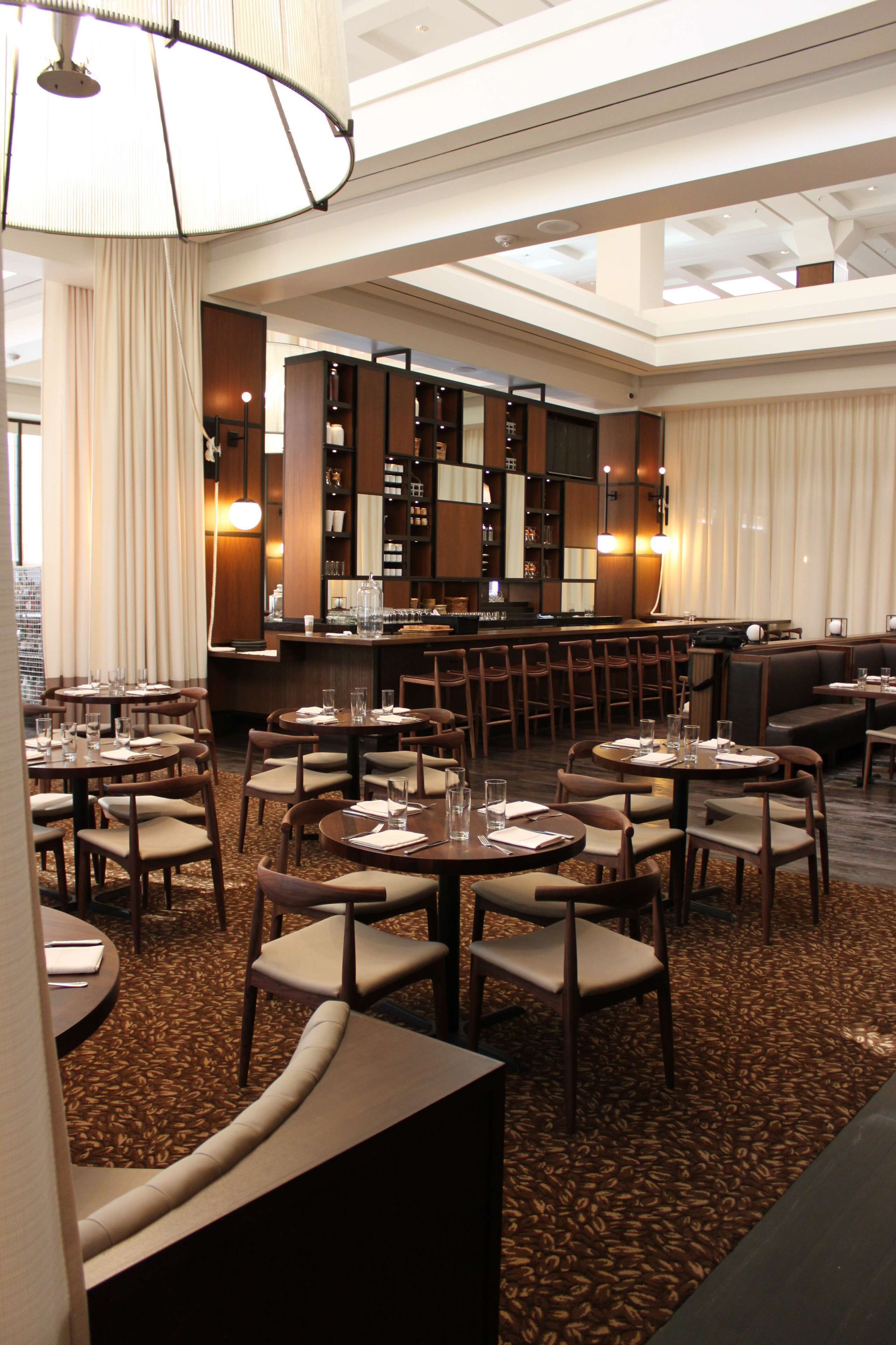 Un espace de restauration d’hôtel comprenant plusieurs tables et chaises, un bar et un coin salon.