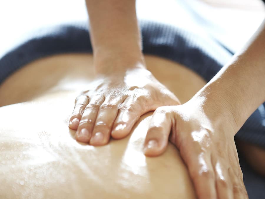 Gros plan sur des mains effectuant un massage sur le dos d’une personne.
