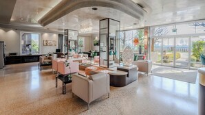 A spacious, modern living area with a high ceiling, large windows, and contemporary furniture. - Antony Hotel (Mestre)
