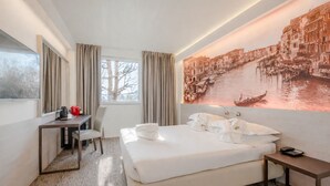 A hotel room with a bed, a desk, a chair, a bedside table, and a large window. - Antony Hotel (Mestre)