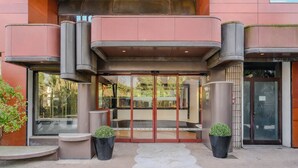 A modern building entrance with glass doors, a small outdoor seating area, and potted plants. - Antony Hotel (Mestre)