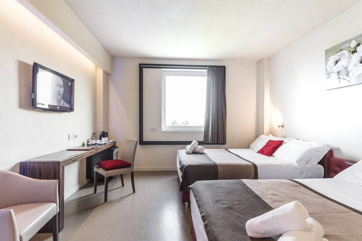 A hotel room with two beds, a desk, and a chair.
