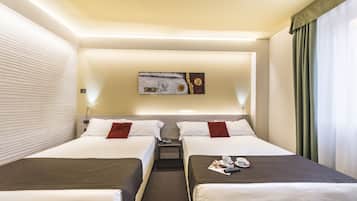 A hotel room with two beds, a small table, and a painting on the wall.