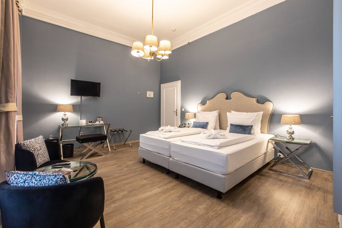 Une chambre d’hôtel moderne, dotée d’un grand lit, d’un bureau, d’une télévision et d’une table en verre avec une chaise.