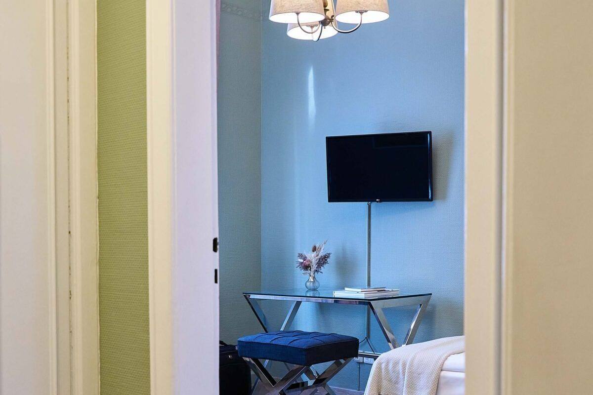 Une pièce comprenant un lit, un bureau avec une chaise, un téléviseur fixé au mur et un luminaire suspendu.