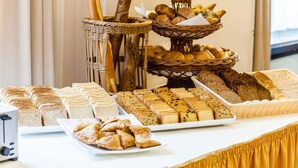 A buffet table with various breads, pastries, and sandwiches.