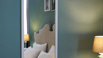 A bedroom with a bed, a nightstand, a lamp, and a mirror on the wall.