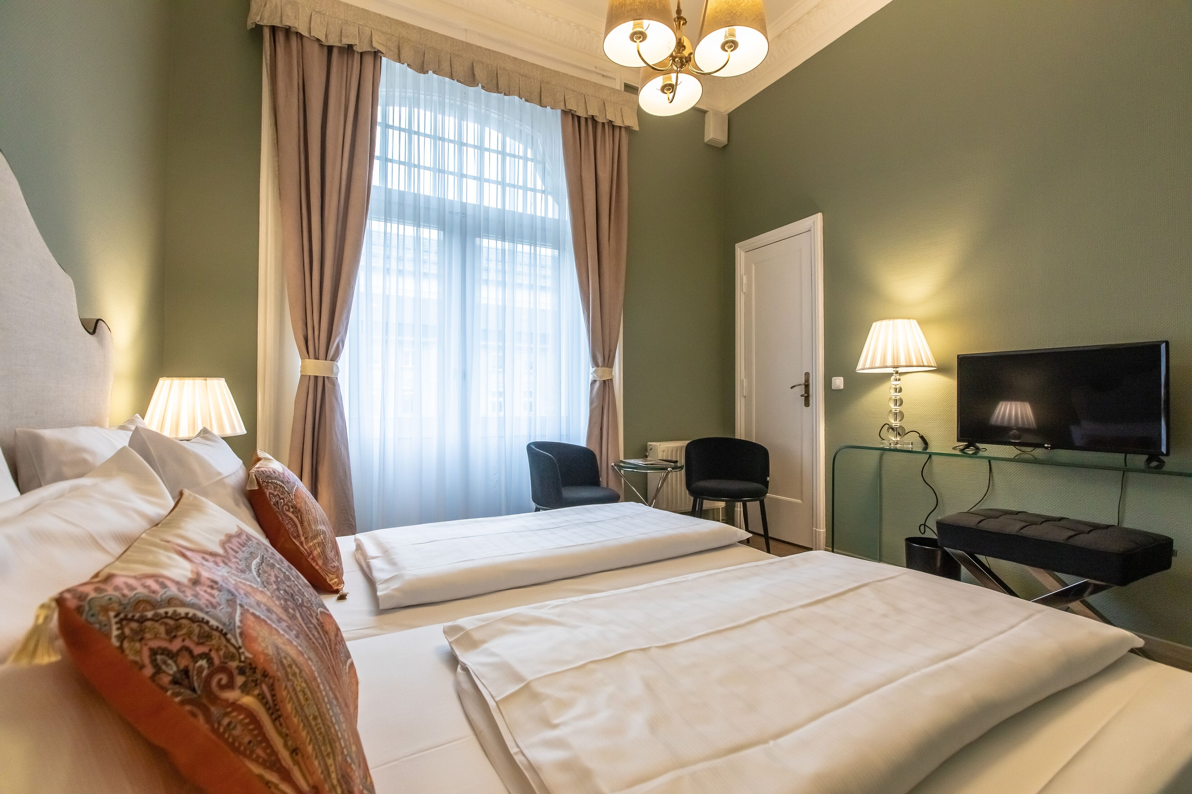 A hotel room with two beds, a television, a desk, and a chair.