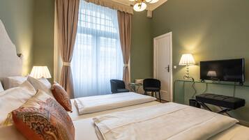 Una habitación de hotel con dos camas, televisión, escritorio y una silla.