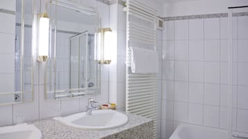 A bathroom with two sinks, a mirror, a towel rack, and a shower.