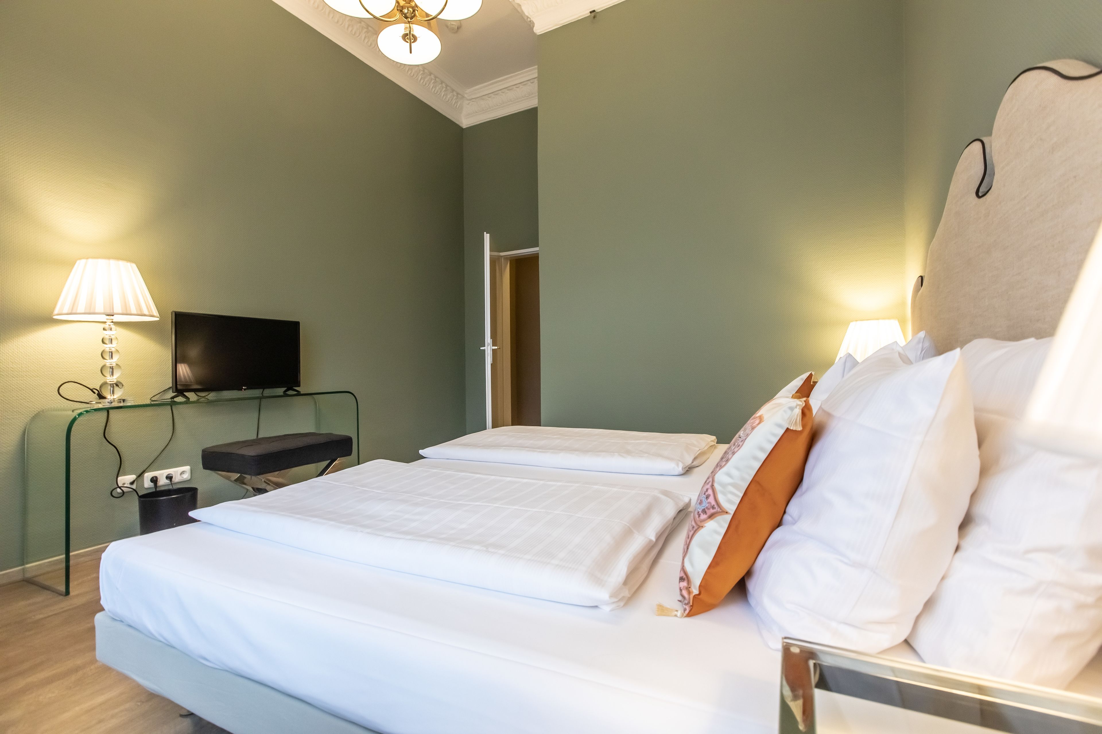 Een hotelkamer met twee bedden, een televisie, een bureau en een lamp.