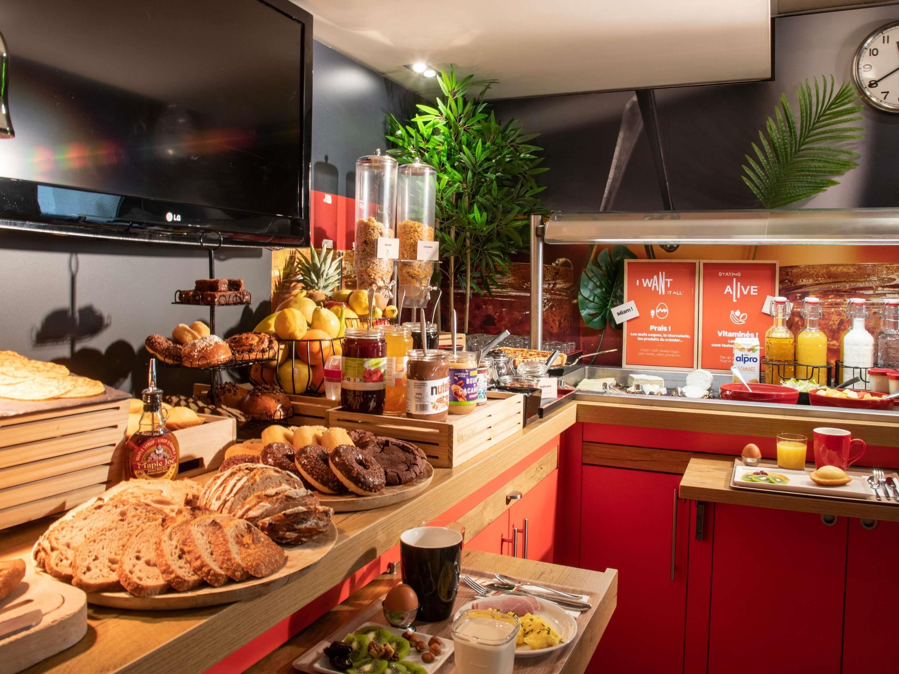 Un buffet per la colazione con diversi cibi, una sveglia e una televisione a parete.