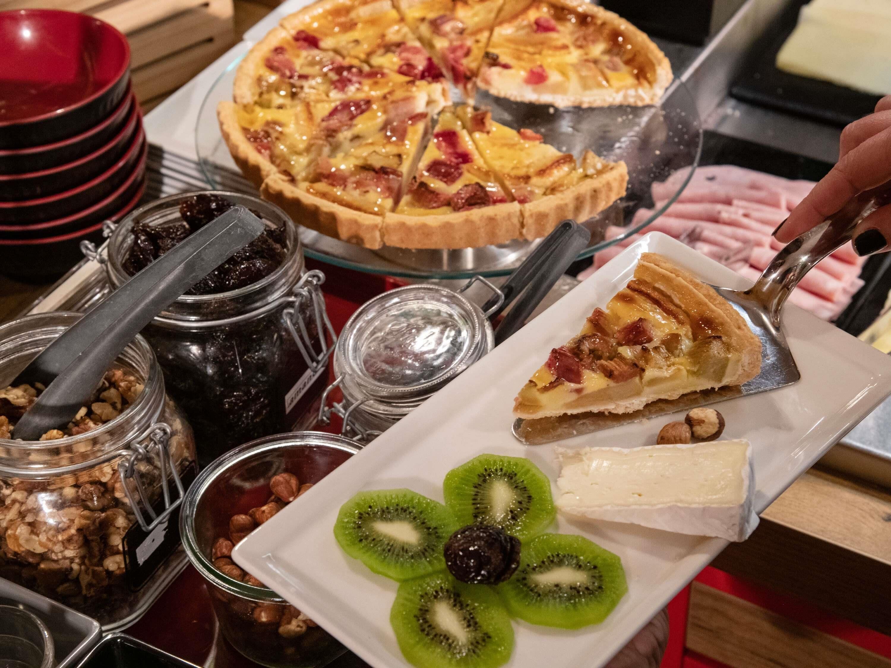 A dessert platter with a slice of pie, kiwi slices, and a piece of cheese on a white plate.