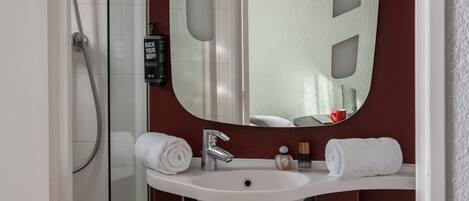 A bathroom with a white sink, a mirror, and a shower.