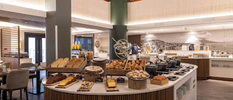 A buffet counter with various baked goods and pastries.