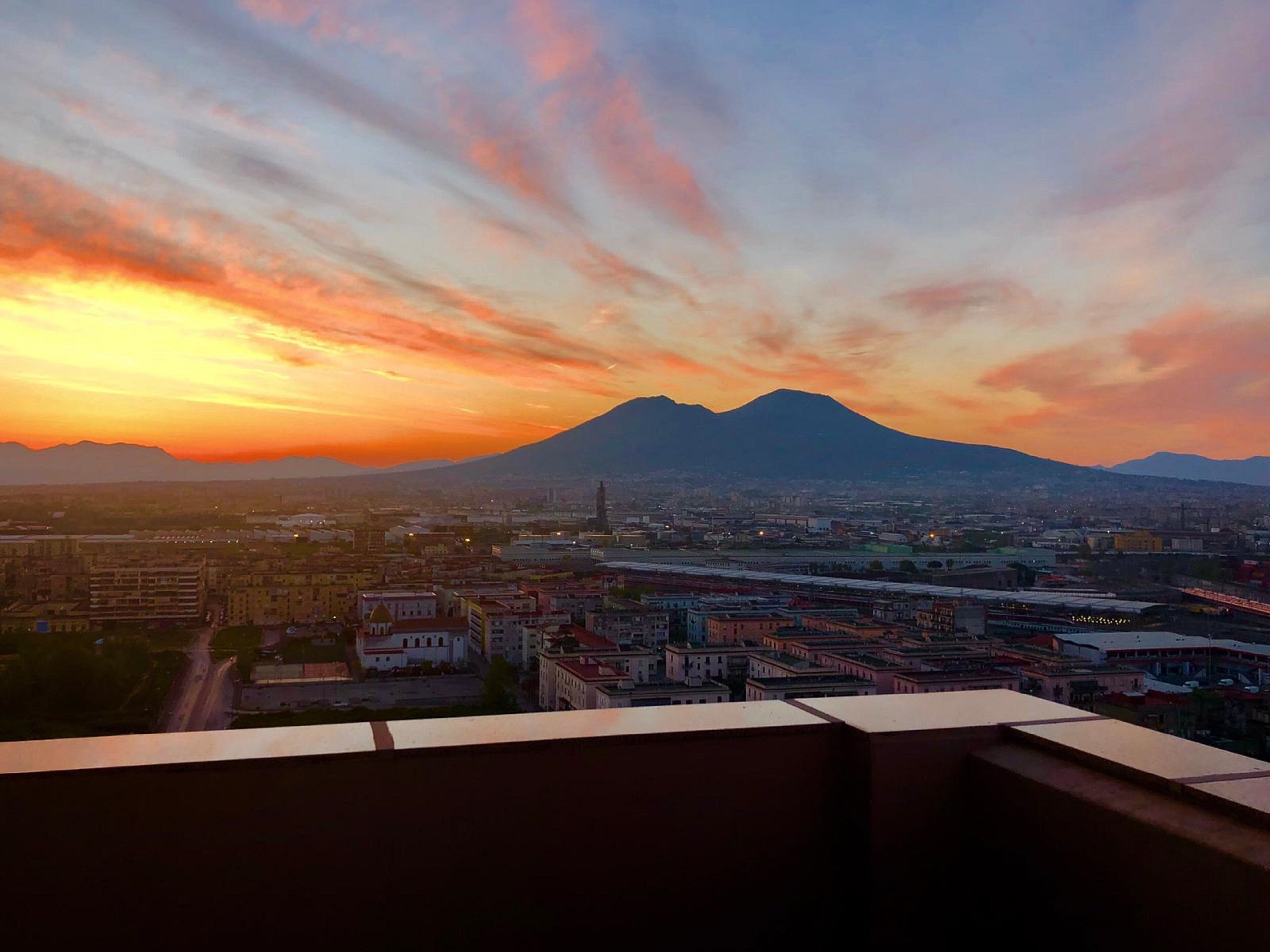A cityscape with a mountain in the background during sunset.