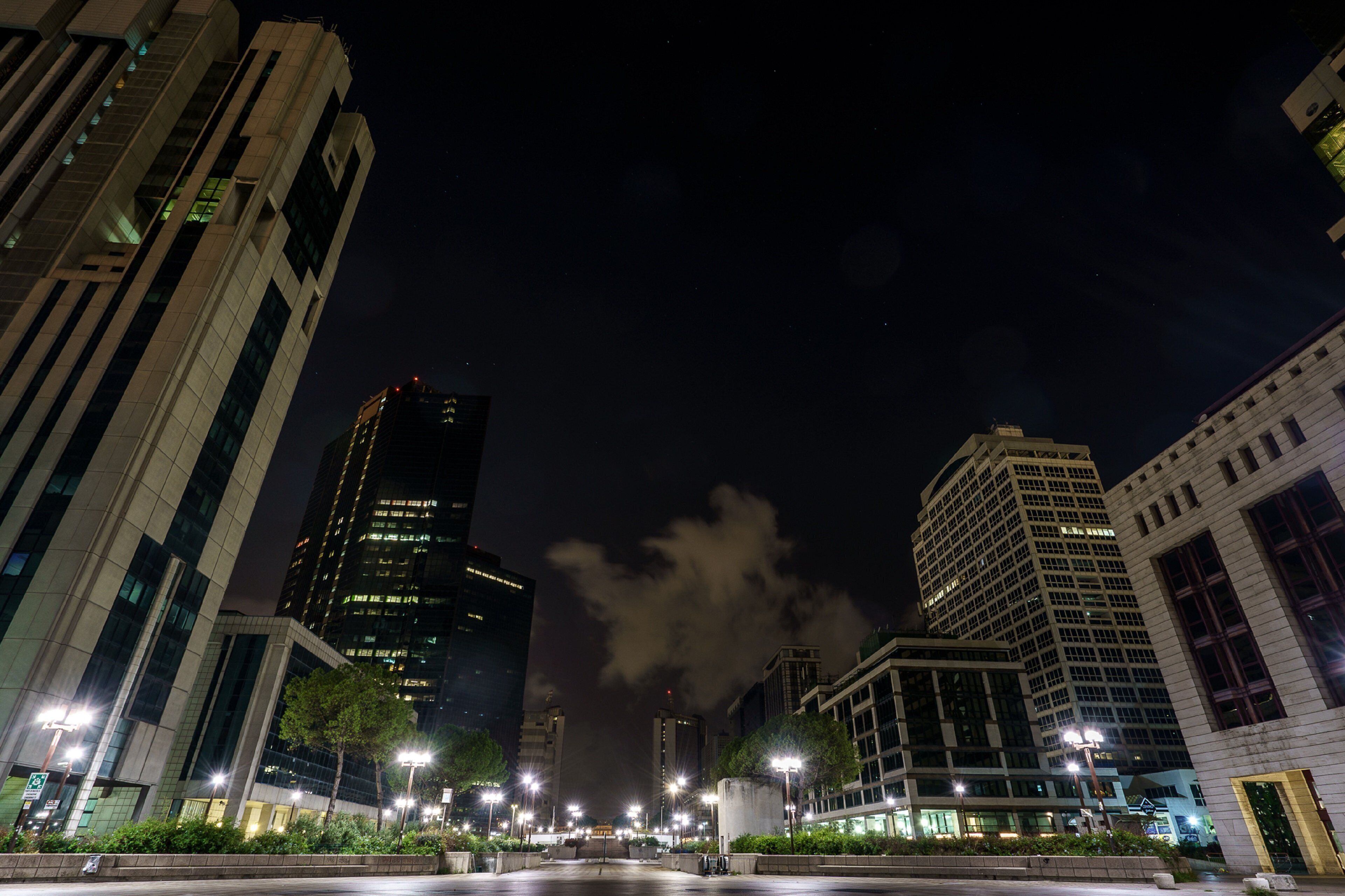 A nighttime cityscape with modern buildings, streetlights, and a clear sky.