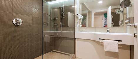 Un baño moderno con ducha de vidrio, lavamanos blanco y espejo grande.