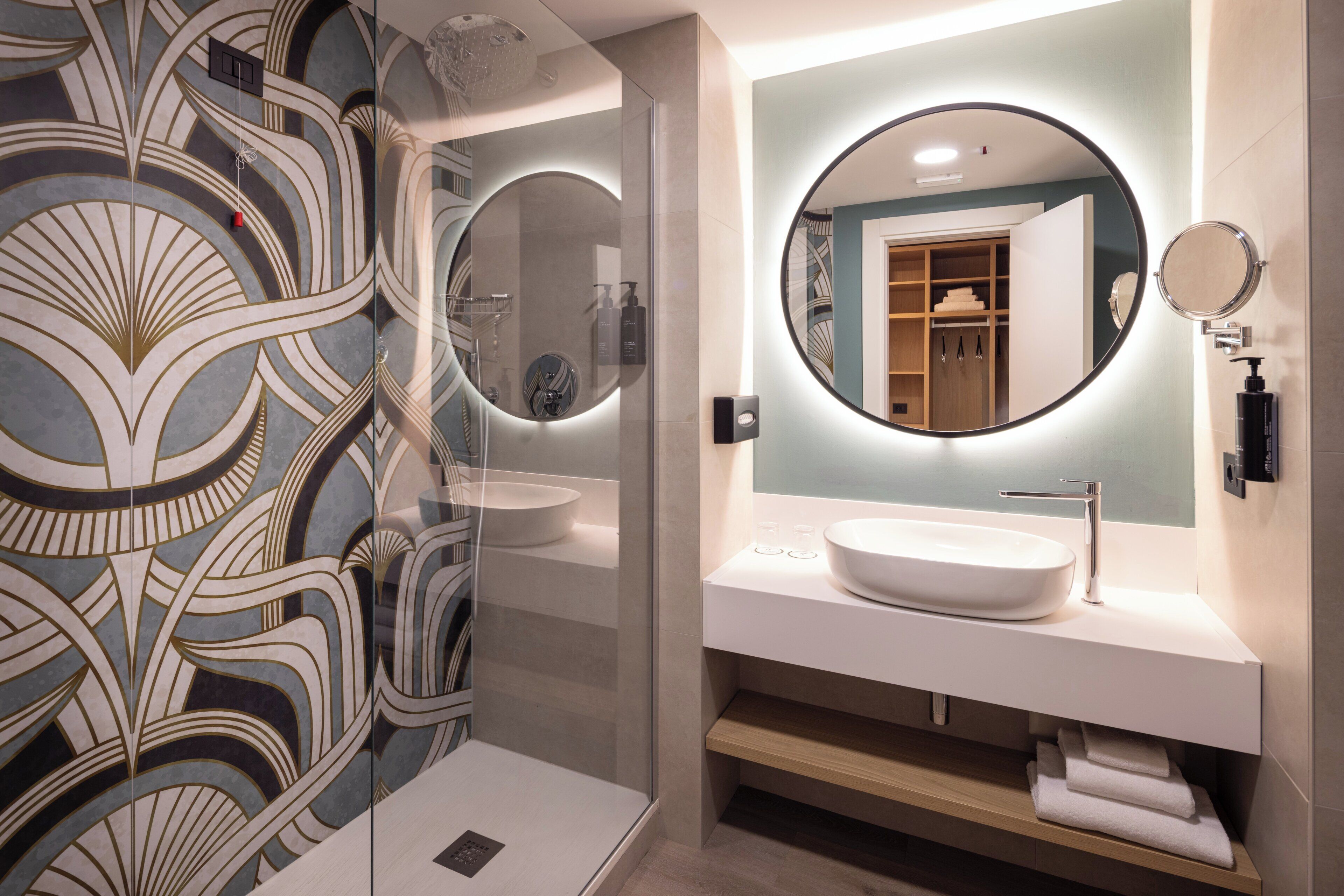 A modern bathroom with a large mirror, two sinks, and a decorative wall.