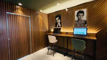 Una habitación moderna con pared de listones de madera, dos taburetes tipo bar, un escritorio con una computadora portátil y cuadros en la pared.