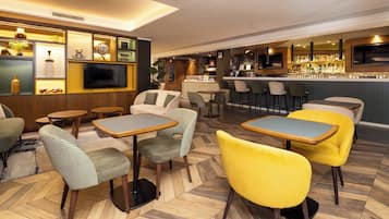 A bar area with multiple seating options, a television, and a bar counter.