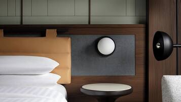 Una habitación de hotel moderna con una cama, una mesa redonda y una lámpara fijada a la pared.