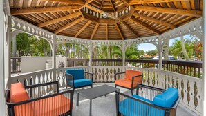 A covered outdoor seating area with wooden beams, white lattice railings, and colorful cushions. - Hampton Inn Fort Myers-Airport & I-75 (Fort Myers)